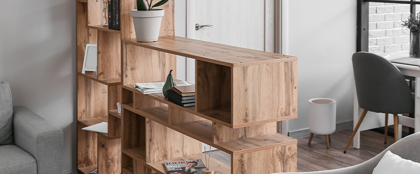A see-through natural wood grain book shelf, used as a partition between a living room and office space. 