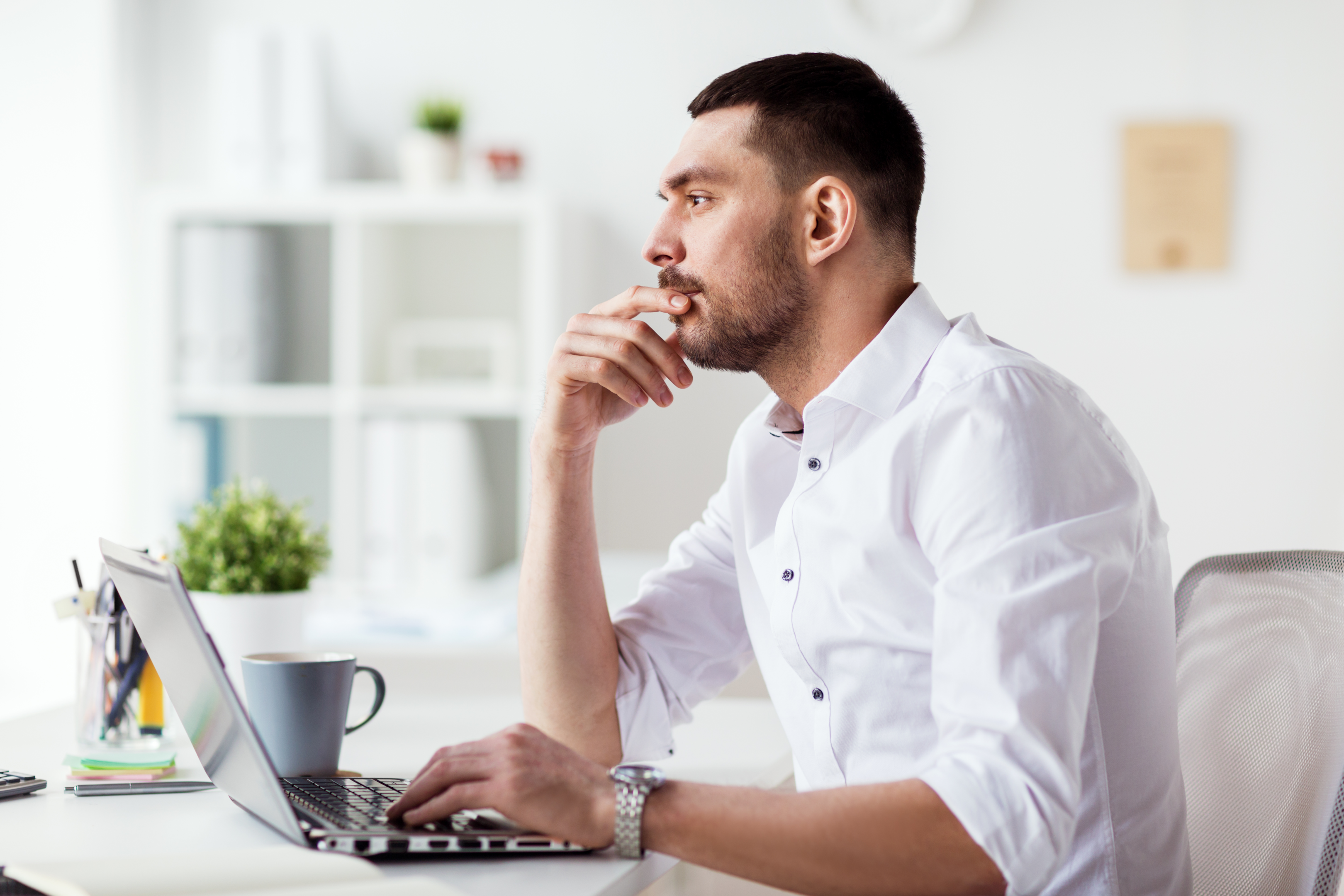 Business man thinking while using laptop