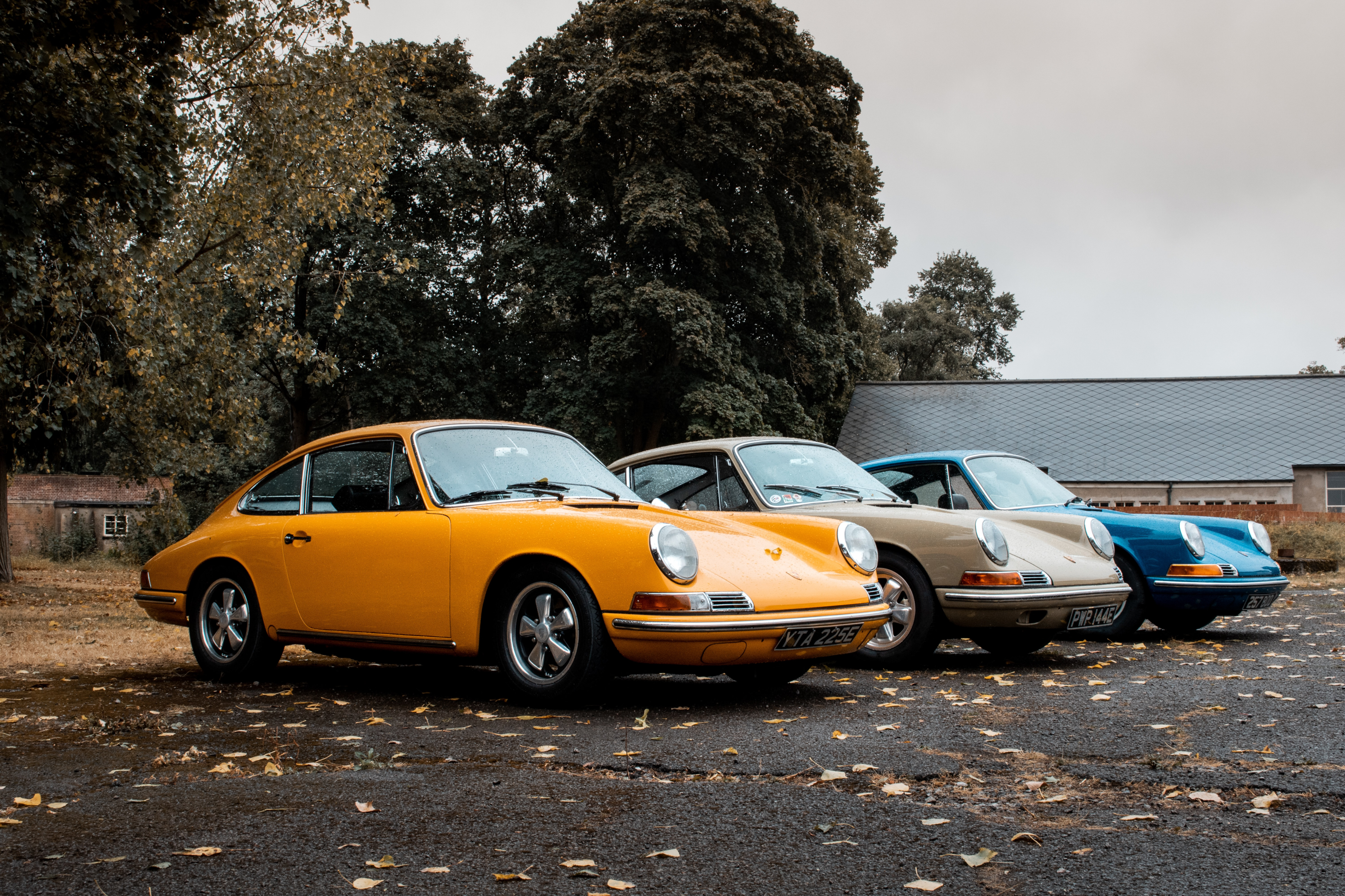 Three 1960s Porsche 911's parked in a parking lot. As the auto transport industry leader, NTS provides both open and enclosed transport.