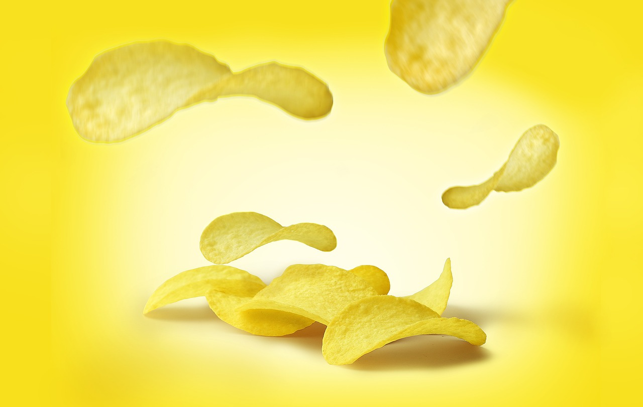 An image of potato chips floating down on a yellow background. 