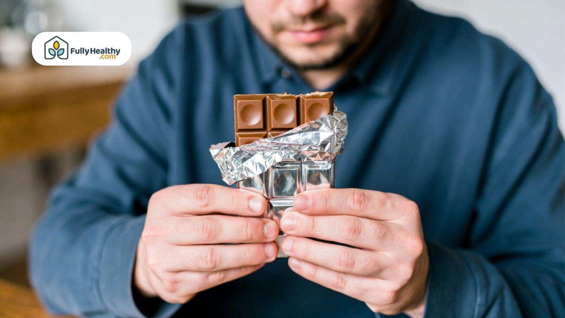Person holding and unwrapping a chocolate bar.