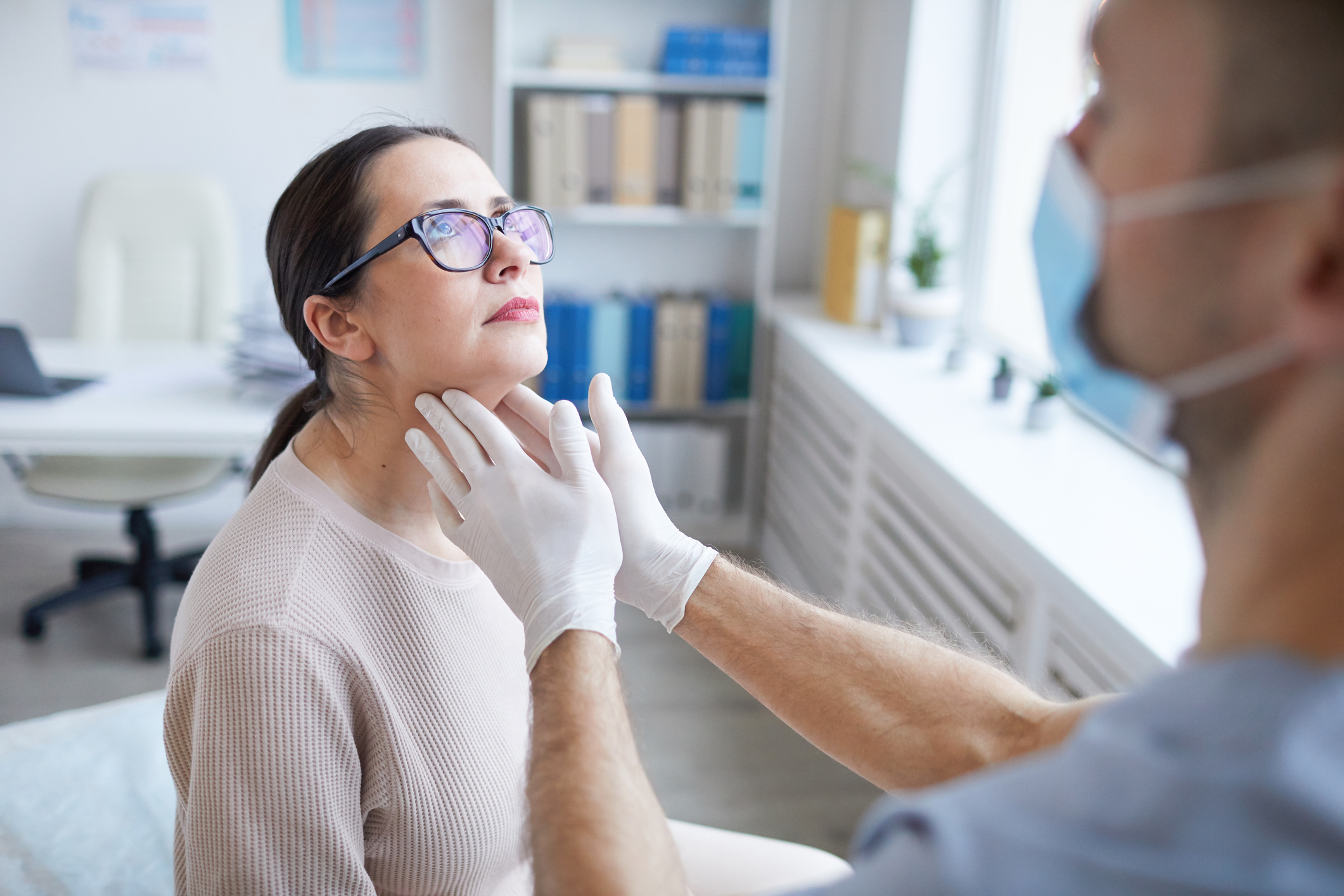 An image of a doctor feeling a patient's throat.