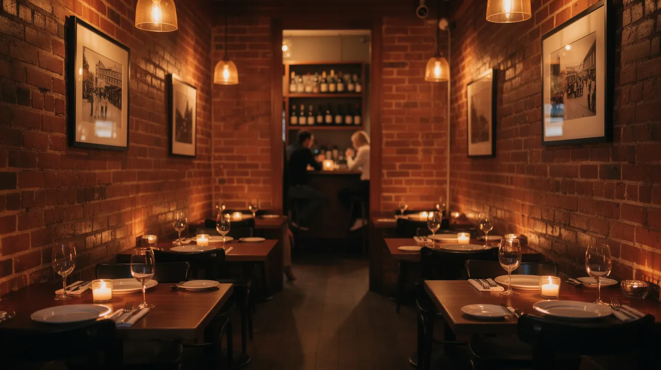 The image depicts a cozy, warmly lit restaurant interior in Philadelphia, featuring exposed brick walls and candlelit tables, creating an intimate atmosphere perfect for a romantic date night. Guests can enjoy a delightful meal while sharing conversation over a good selection of wine and small plates in this charming spot in Center City.