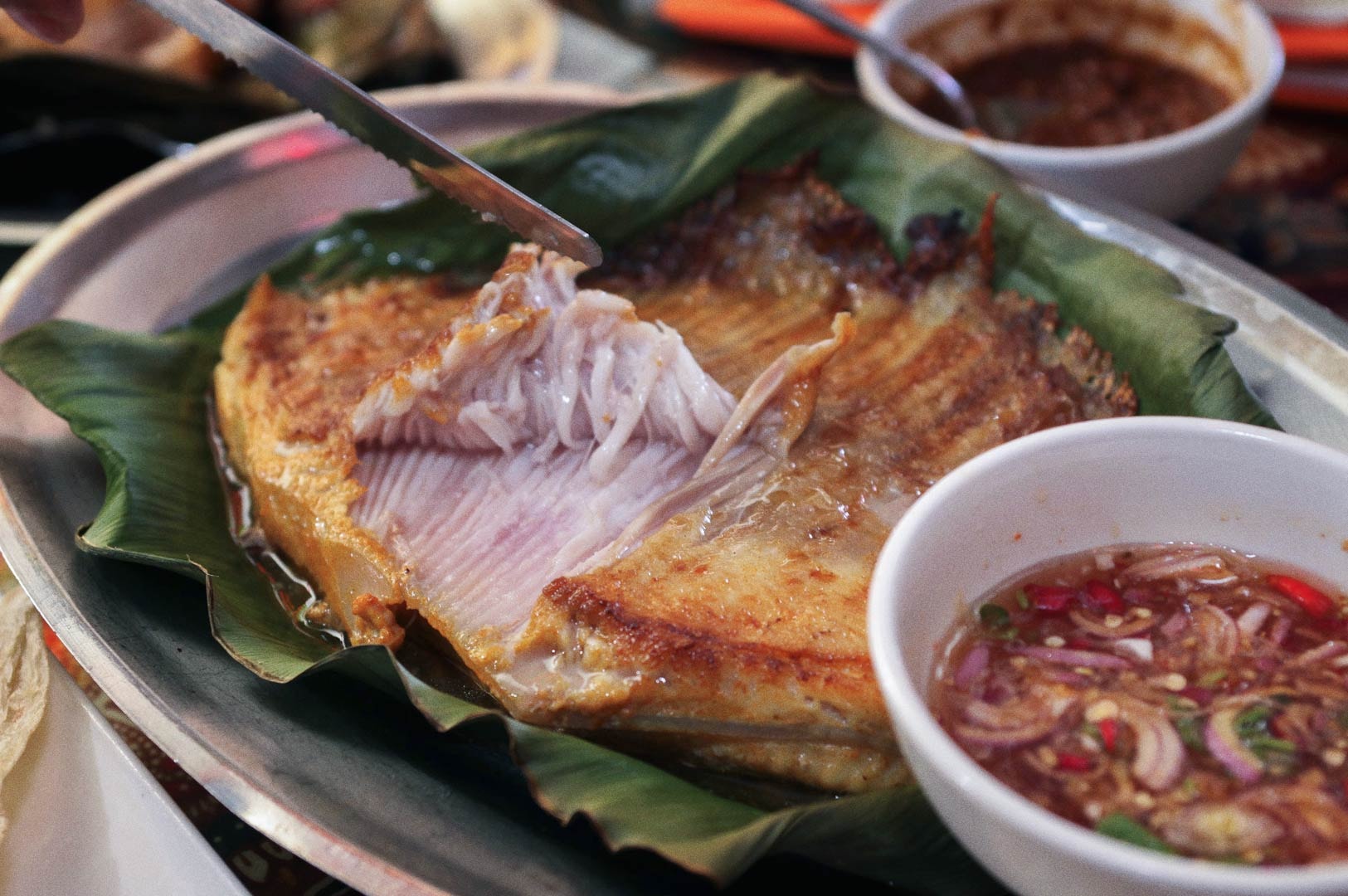 Sambal Stingray served on banana leaf with spicy dipping sauces.