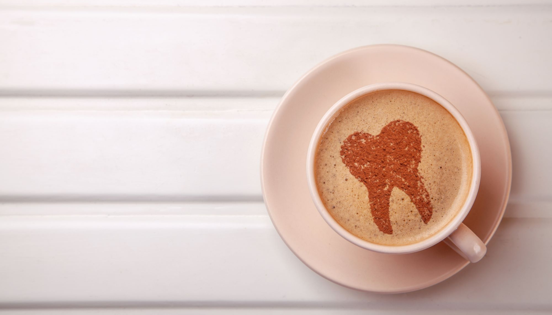 Kaffe etter tanntrekking: Hvorfor du bør vente litt med favorittkoppen 11 Kaffekopp med tannformet kakaomønster på skummet, plassert på lys tallerken mot hvit bakgrunn.