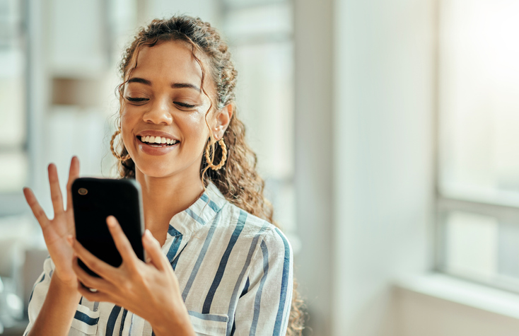 Pretty young woman in a blue and white striped shirt reading a text message. 