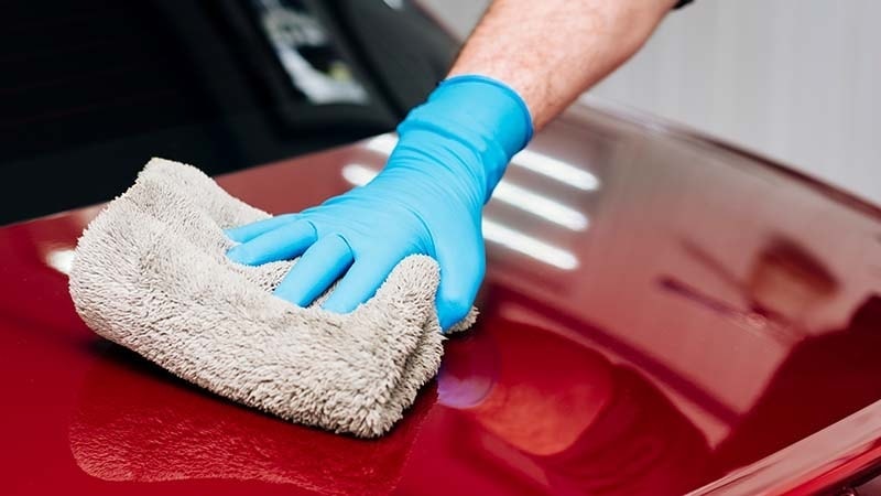 drying a red car with a microfiber towel
