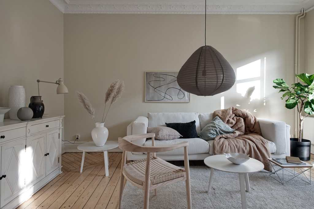 Material alami berupa kayu, jalinan rotan, dan tanaman hijau pada ruang keluarga warna beige, via cocolapinedesign