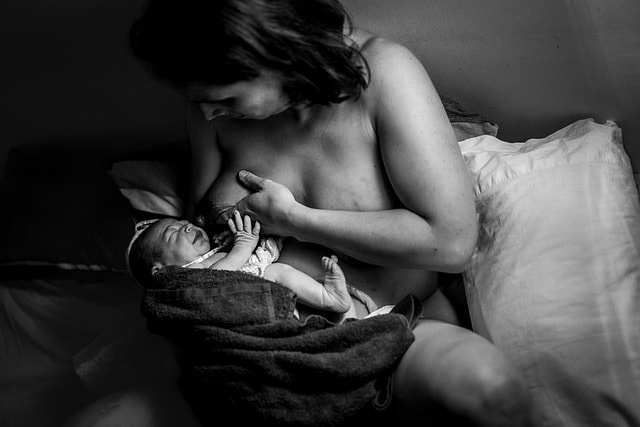 Mother demonstrating proper breastfeeding technique to prevent mastitis