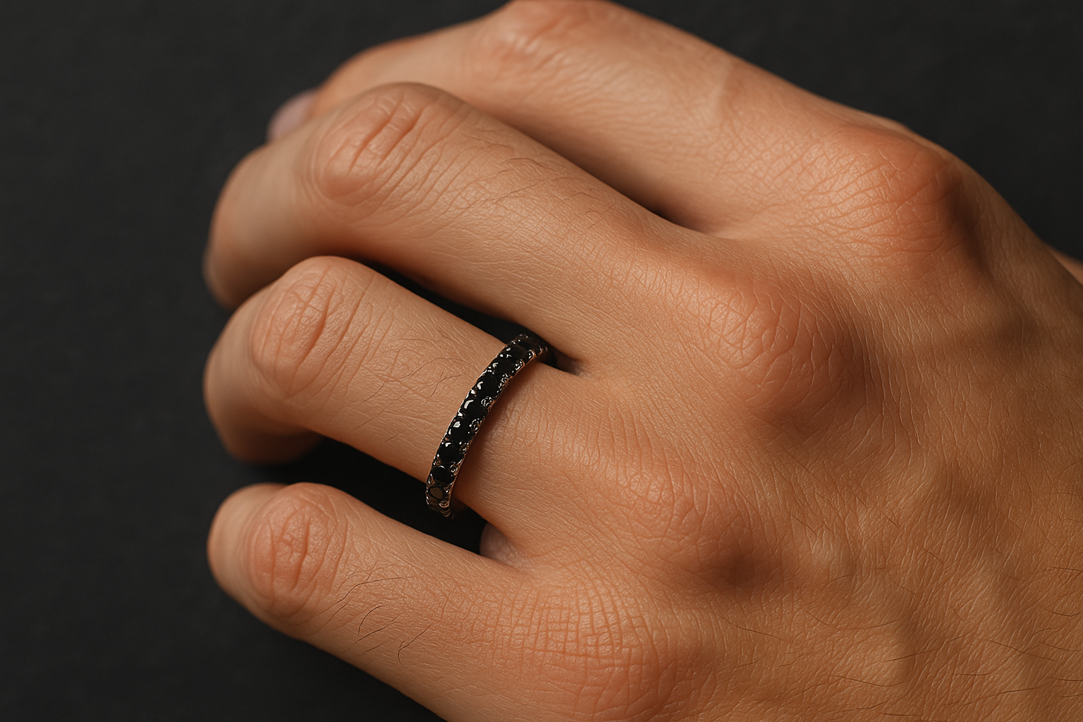 Deimantinė juostelė su juodais deimantais ant vyriškos rankos, tamsiame fone.