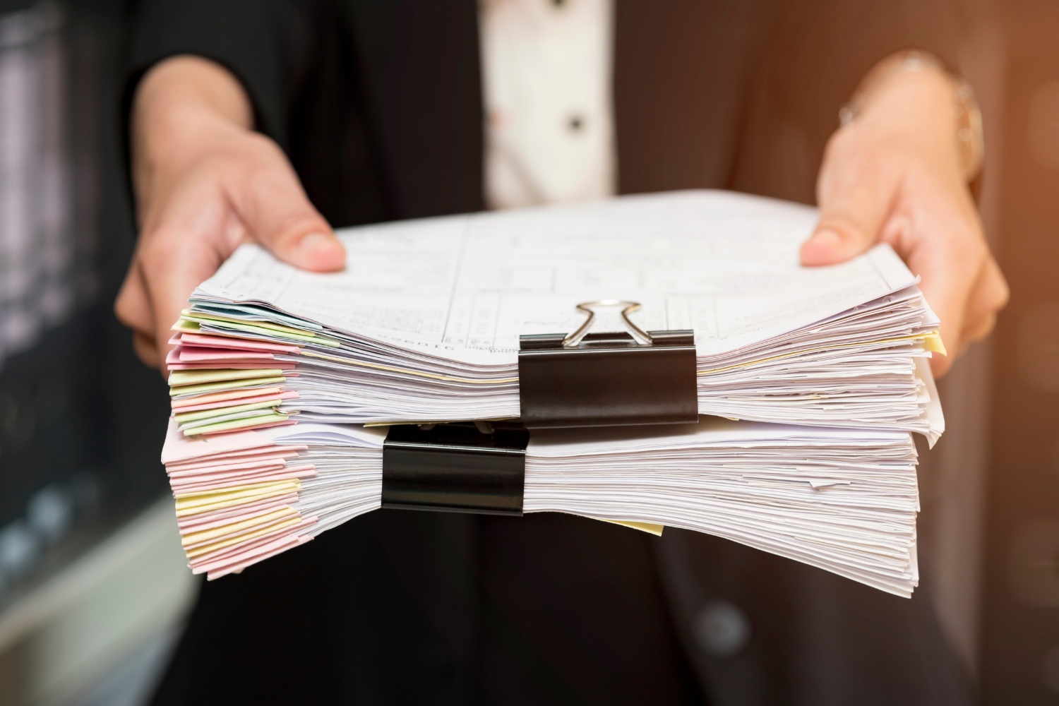Person in a suit holding a stack of papers. Vet a liquid dietary supplement manufacturer for quality, certifications, and compliance.