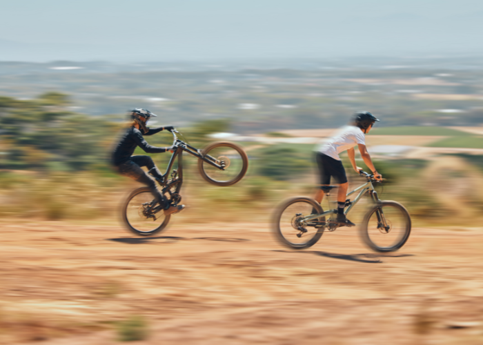 A mountain biker taking their wheelie skills to the trail, with ideal road grade, gear selection and brake control