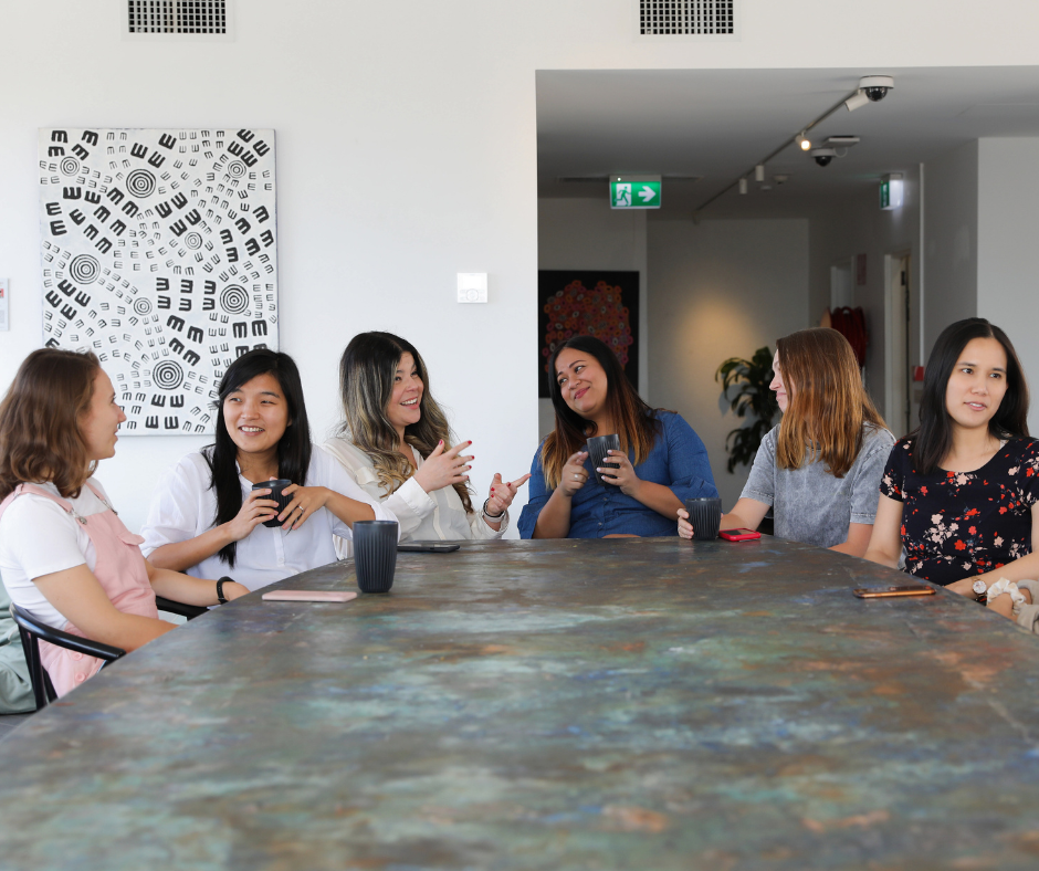 six women sit around a large table in an office