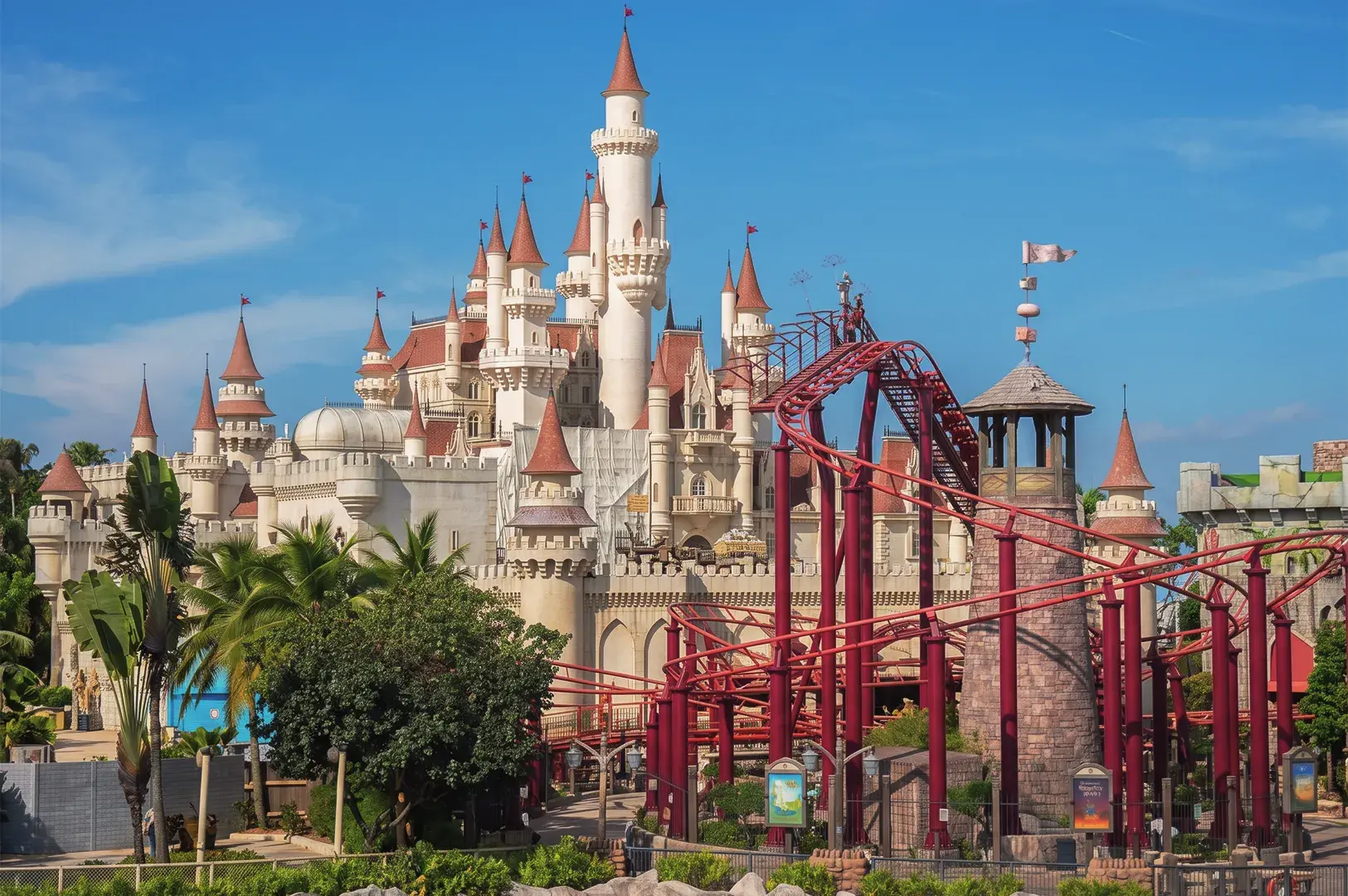 Far Far Away Castle and red roller coaster at Universal Studios Singapore, showcasing fantasy architecture and thrilling rides under clear blue skies.