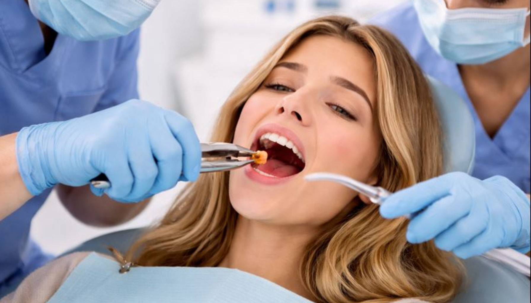 Trekke Visdomstann Nede: Hva Du Bør Forvente 13 Visdomstann fjernes av tannleger med tang og sugeinstrument, pasient med åpen munn i tannlegestol.