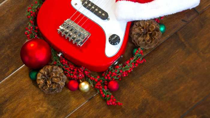 christmas gifts for guitar players. image of a red guitar with holiday gifts and christmas ornamanents around it 