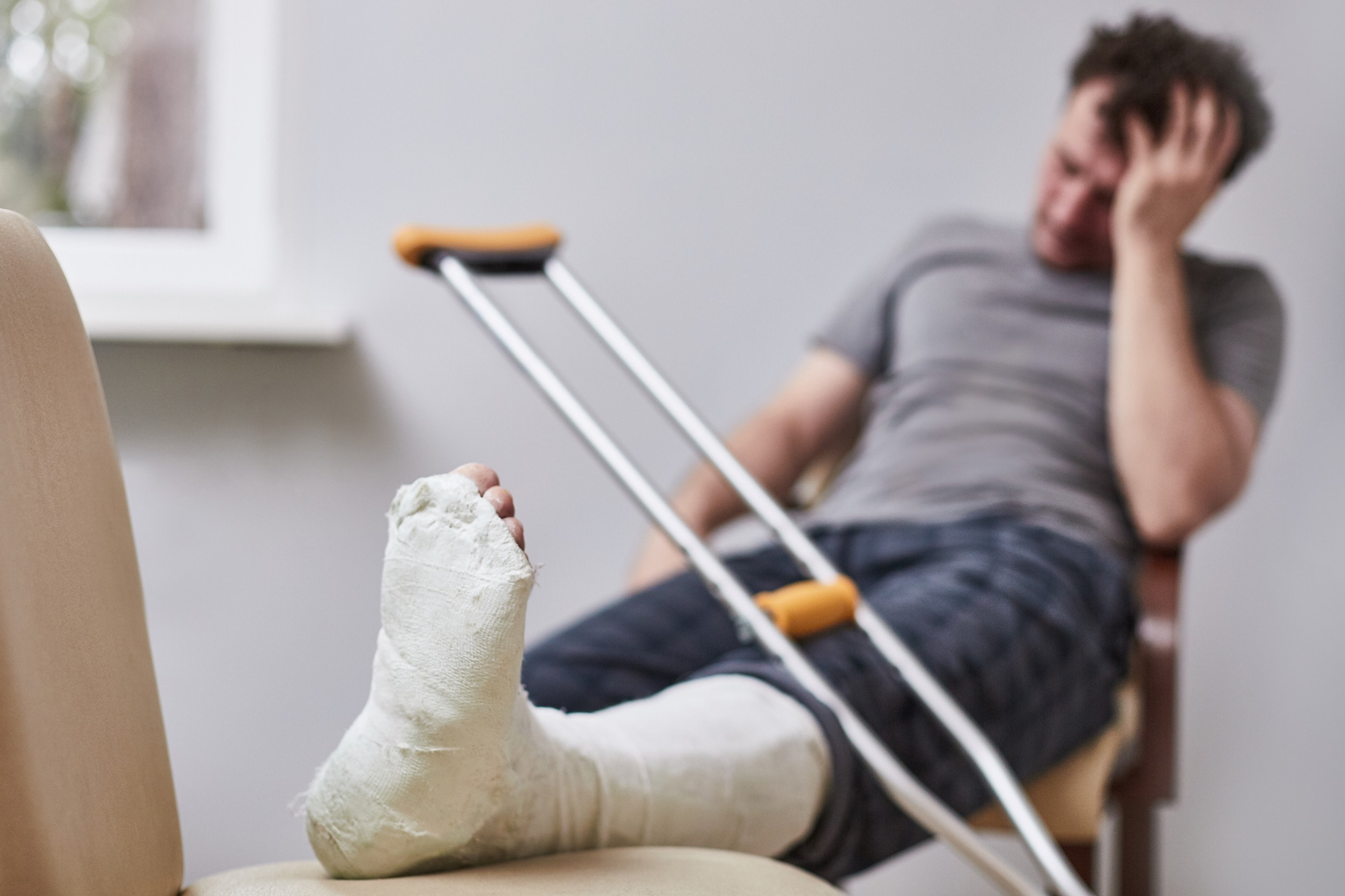 A man sits in a chair with his leg in a cast