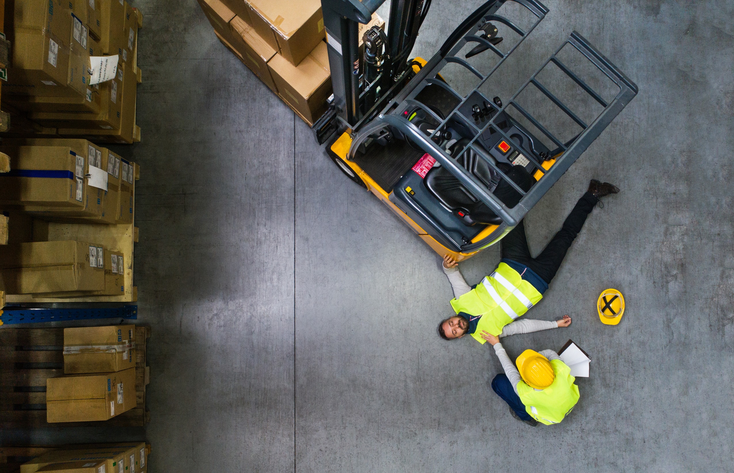 A worker lays unconscious on the floor after an accident happened between two rider operated lift trucks