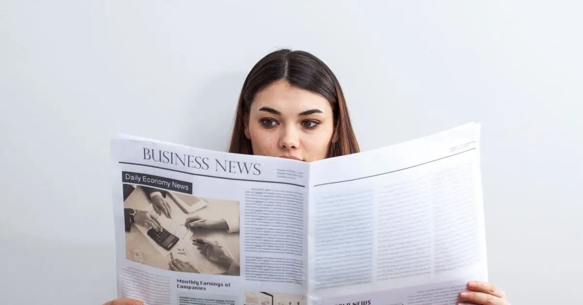 A woman reading a business newspaper, gaining insights from the 2024 tax guide for creators.