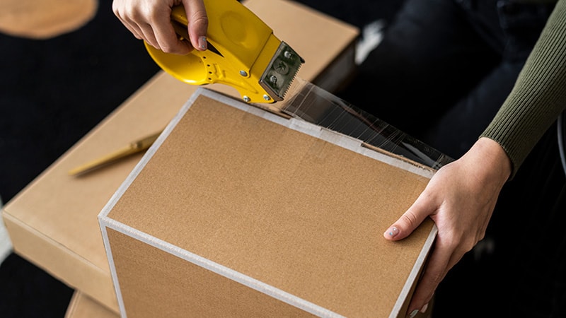 Women sealing the edges of a package with tape