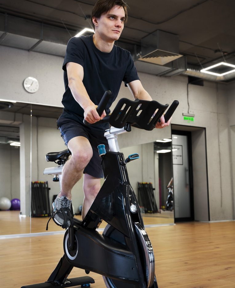 Person tränar på spinningcykel i gymmiljö – effektiv konditionsträning med HE Fitness utrustning.