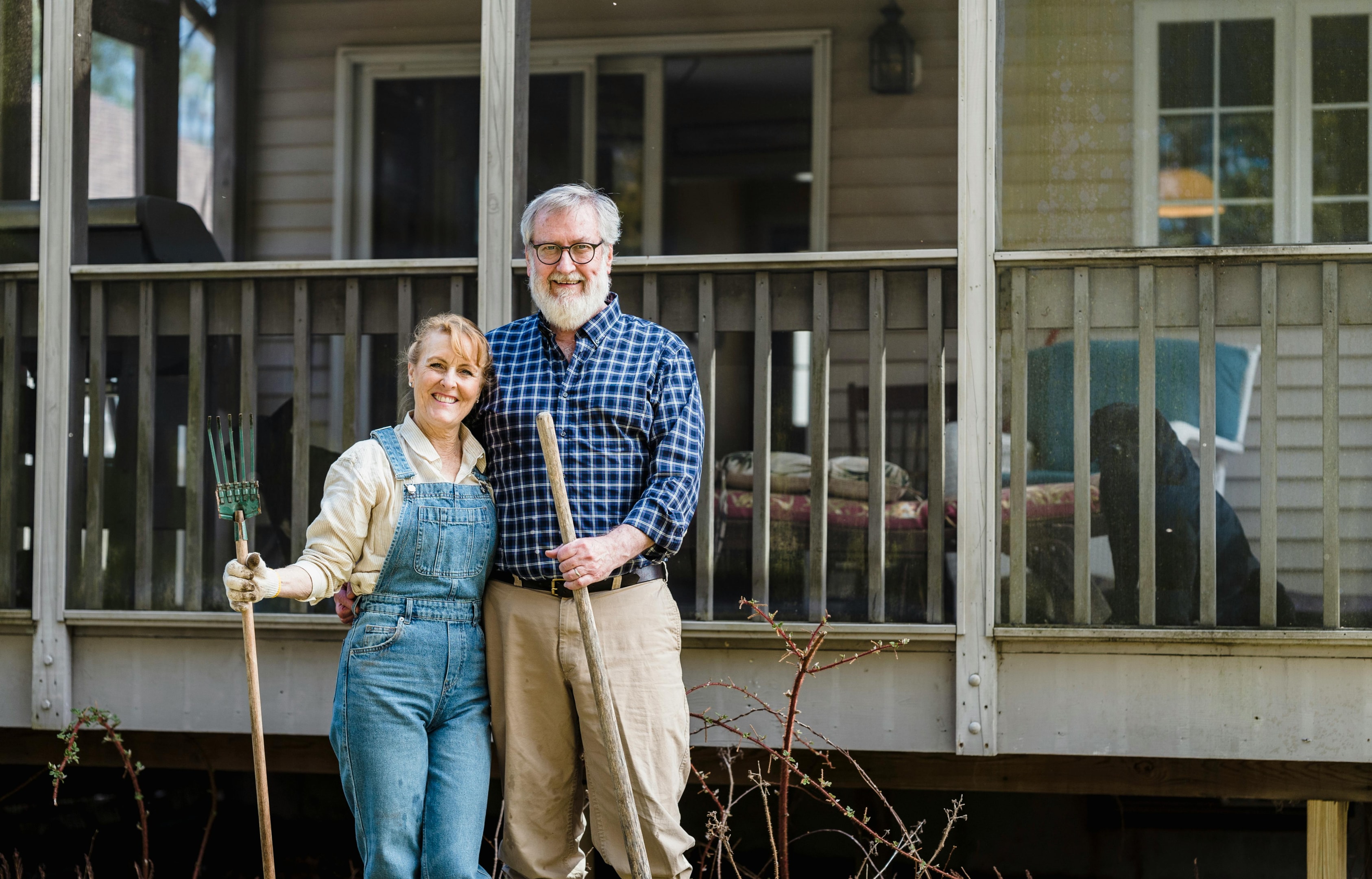 Old couple stands in front of their family home that they've owned for 40 years.