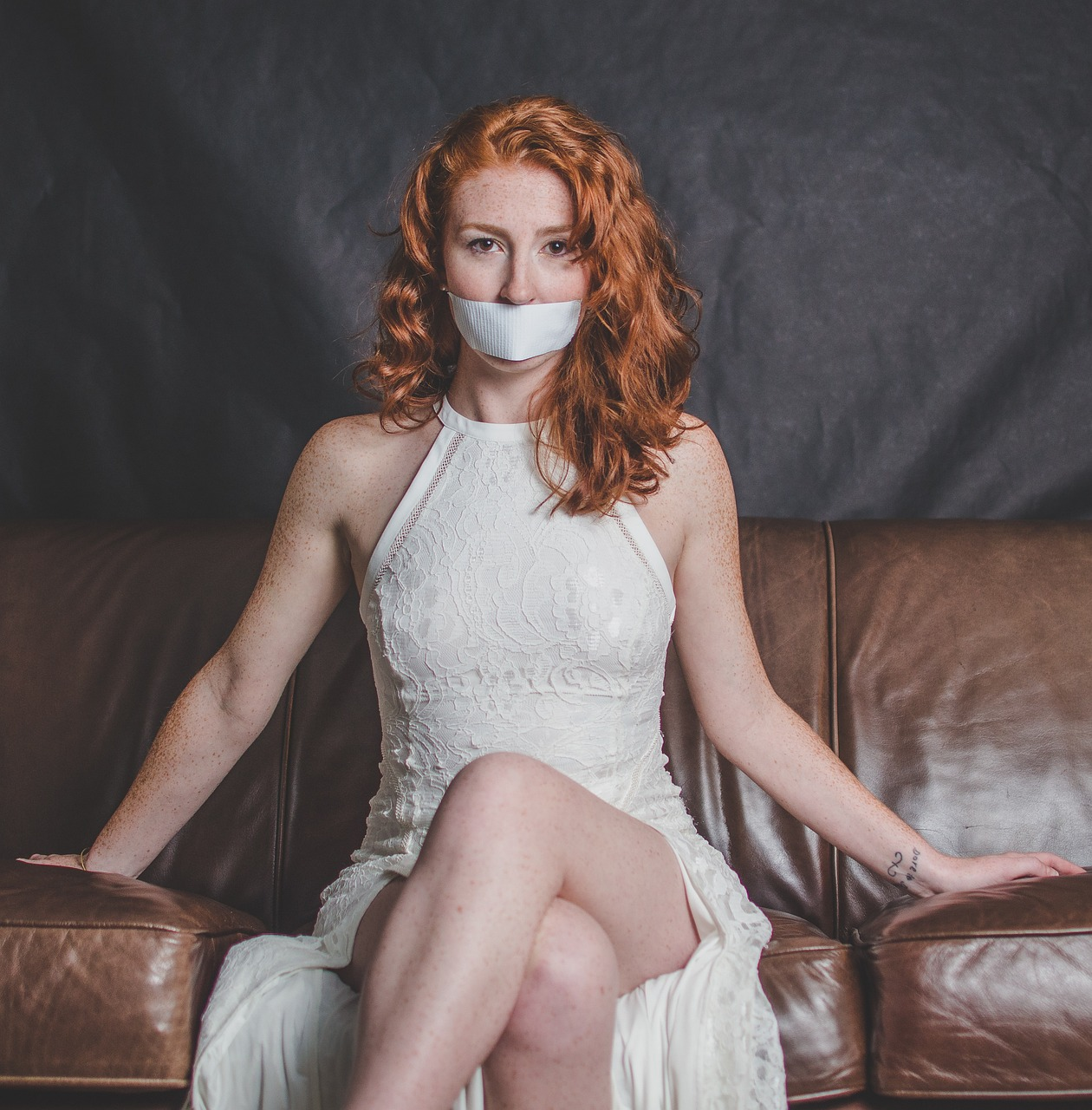 An image of a woman with tape over her mouth symbolizing her need for vocal cord therapy. 