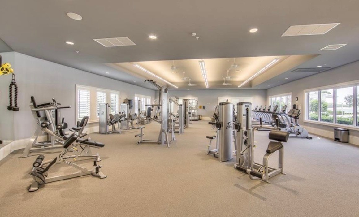 The image depicts a luxurious clubhouse with an infinity pool that offers stunning views of a large lake, situated within the beautiful Corkscrew Shores gated community in Estero, Florida. This resort-style setting features modern designs and amenities, making it an appealing destination for residents and families to enjoy leisure activities.