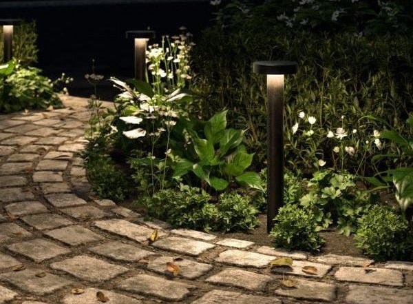 Pathway illuminated by modern outdoor lighting fixtures, highlighting a garden walkway with energy-efficient bollard lights.