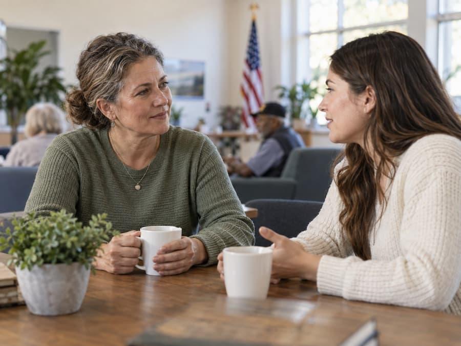 Two women talking over coffee, illustrating how to thank a veteran on Veterans Day.