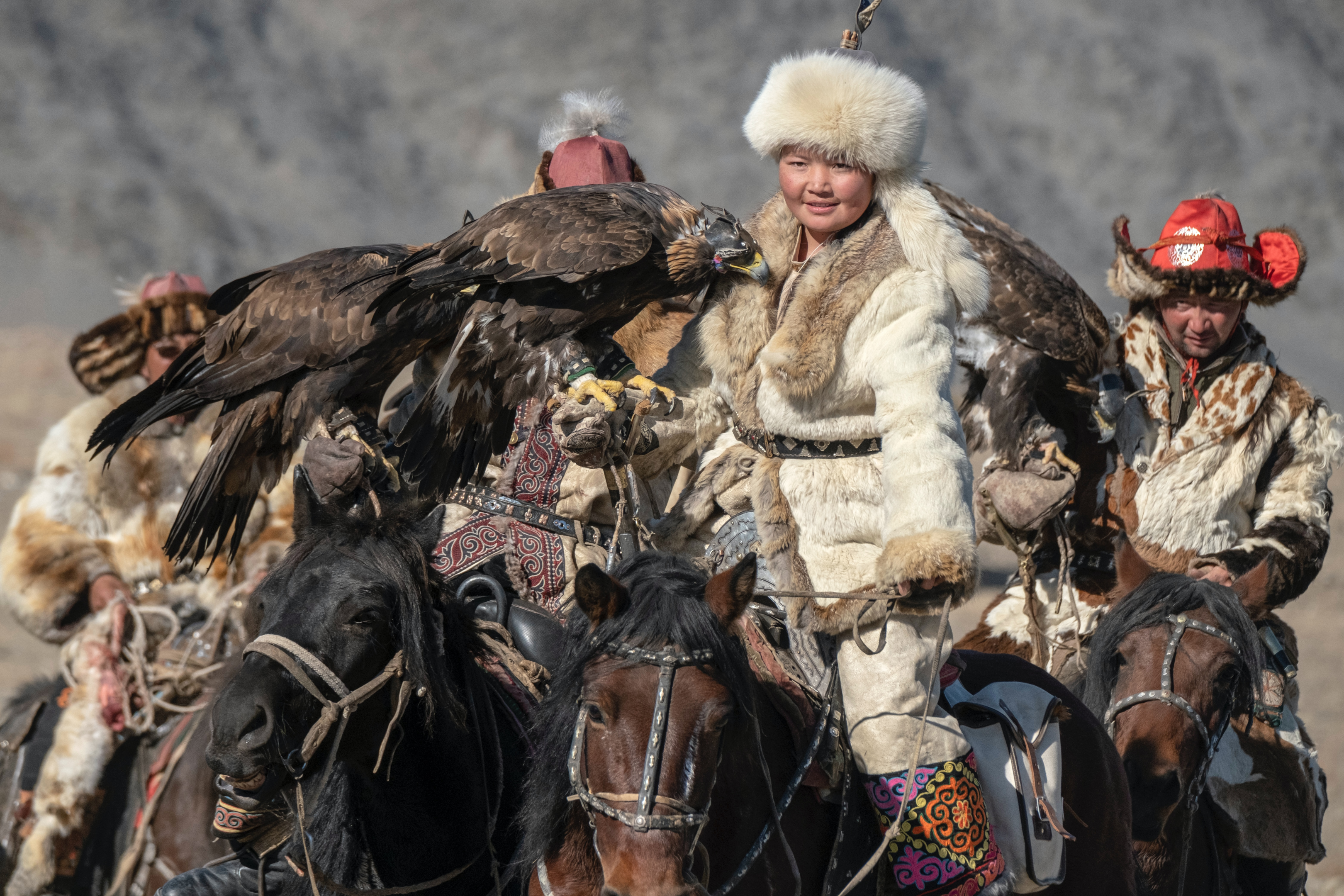 A female eagle hunter with a golden eagle perched on her arm