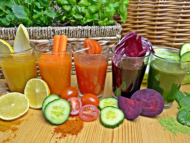 glass of beet juice among other juices with their ingredients laying out