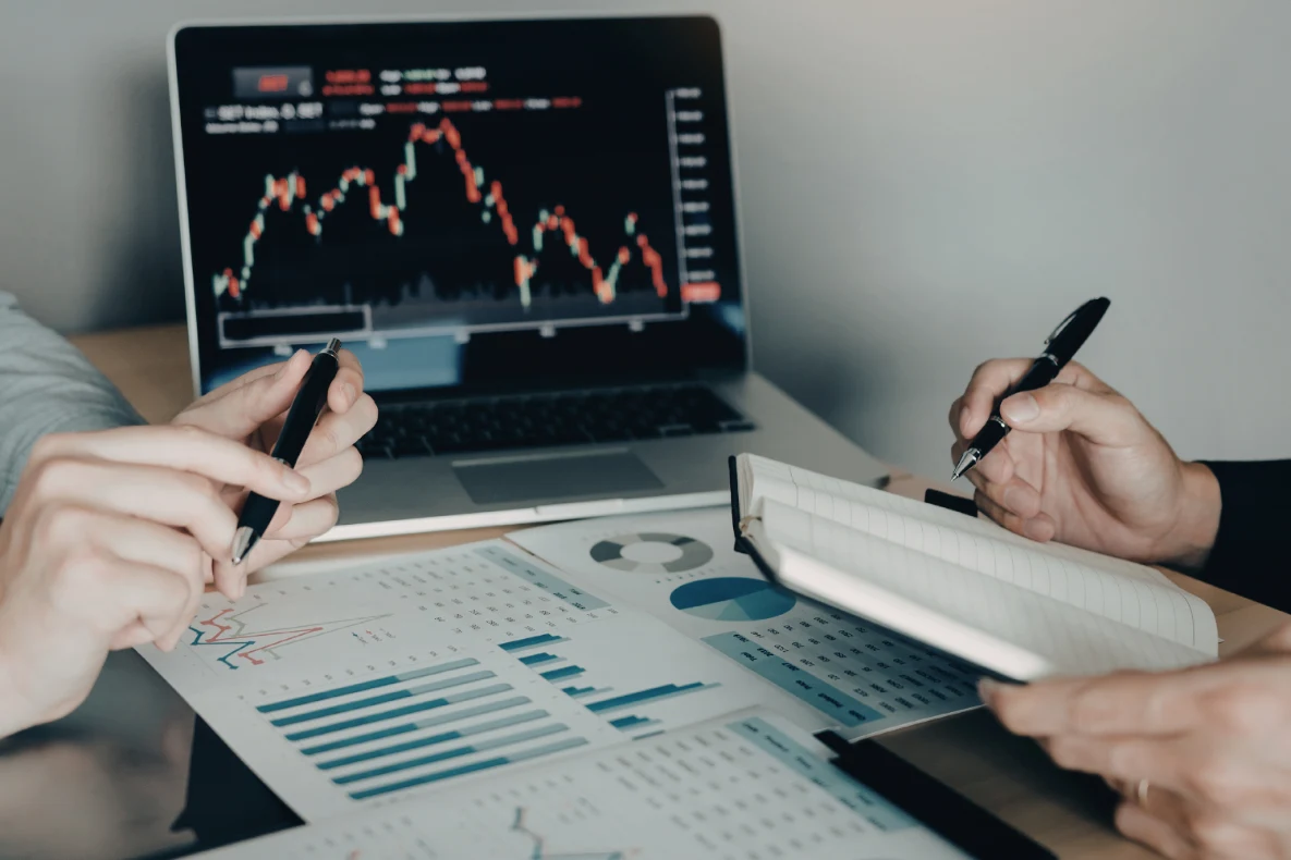 Two people reviewing financial charts and data on a laptop and papers, showing how to determine value of a business.