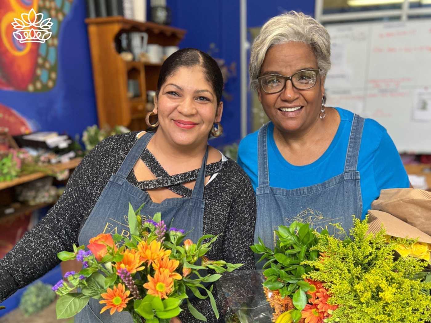 Two smiling florists holding vibrant arrangements from the Flowers By Type Collection at Fabulous Flowers and Gifts store, featuring annuals, seeds, and a diverse range of flowers.