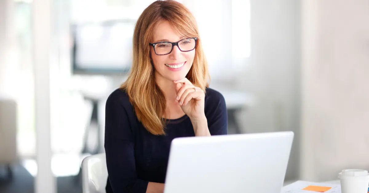 A woman reading at her laptop on how to file a 1099 NEC.