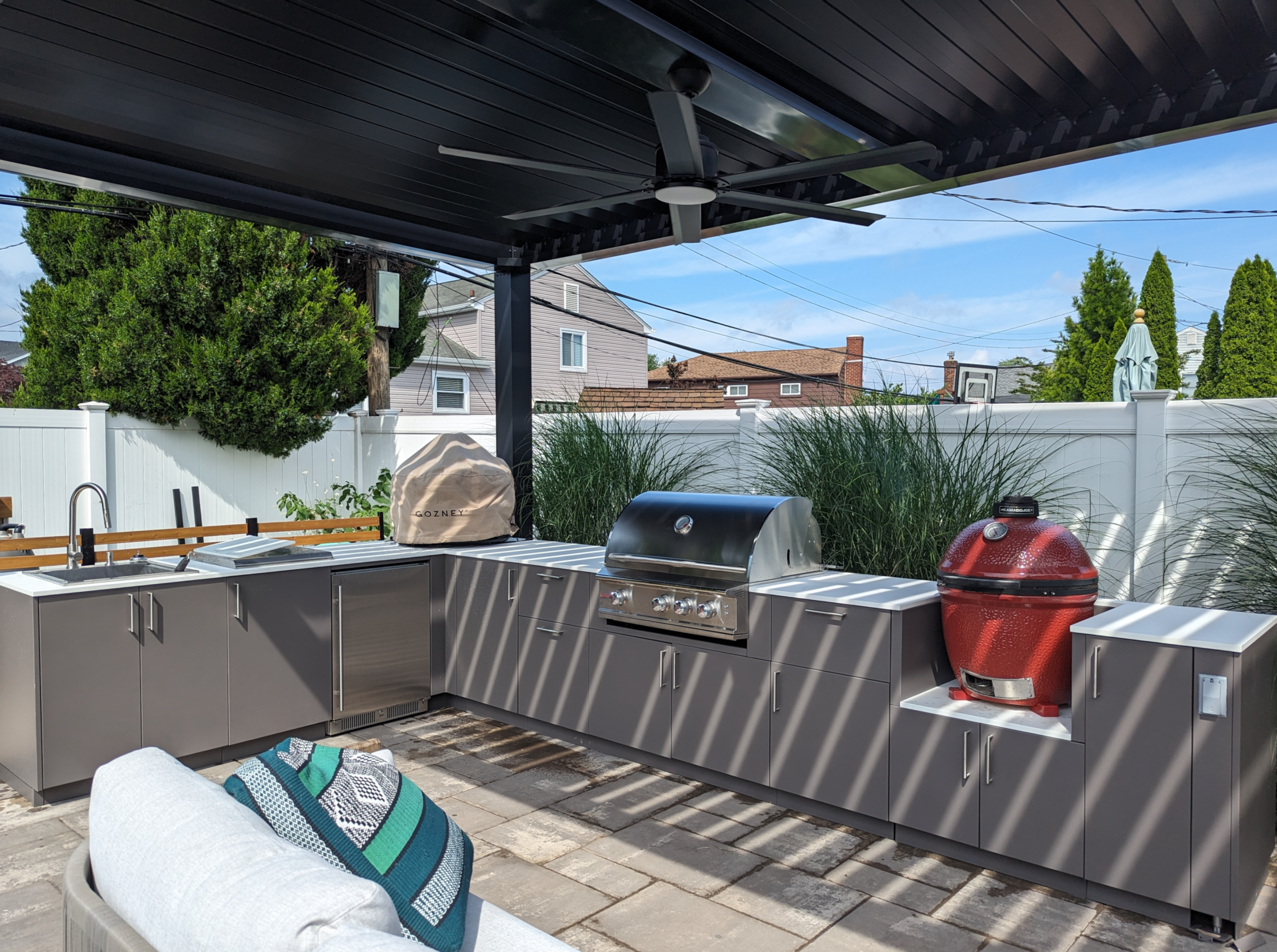 Outdoor kitchen under a pergola with fan.