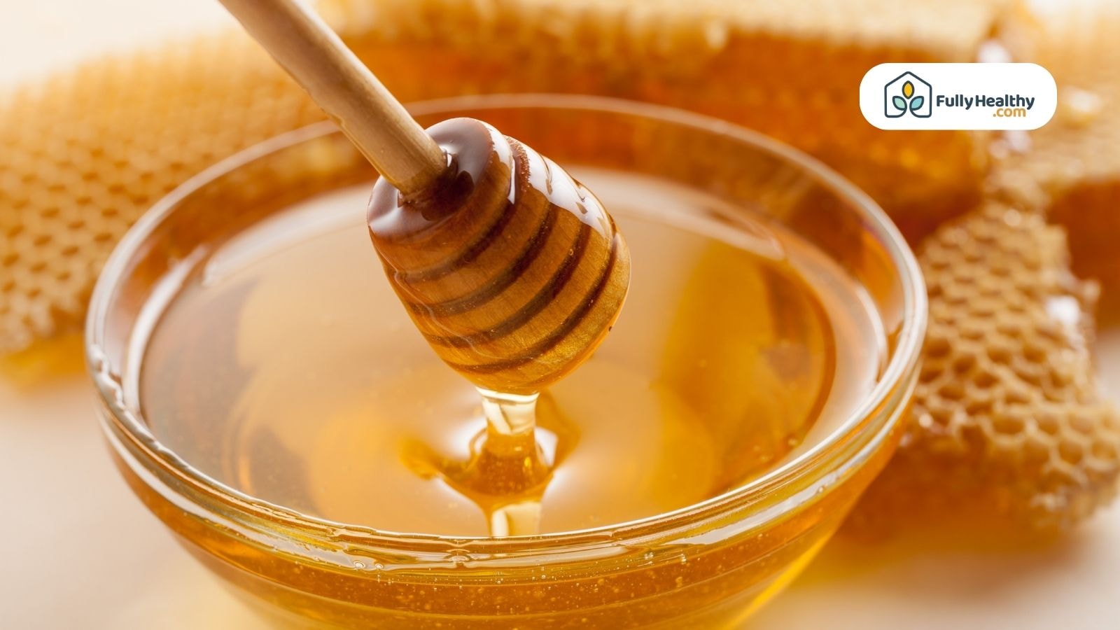 Honey dipper dripping golden honey into glass bowl