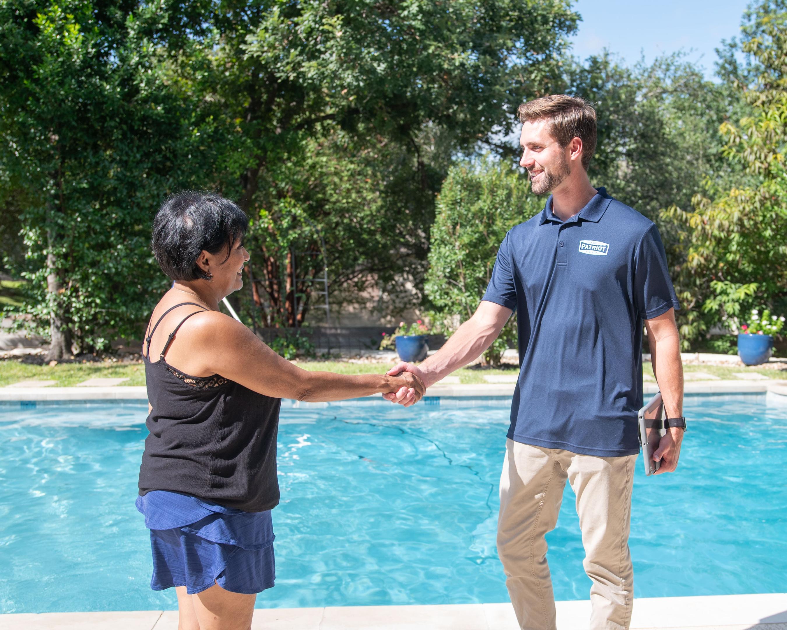 Patriot pool tech greeting customer next to a perfectly clear pool.