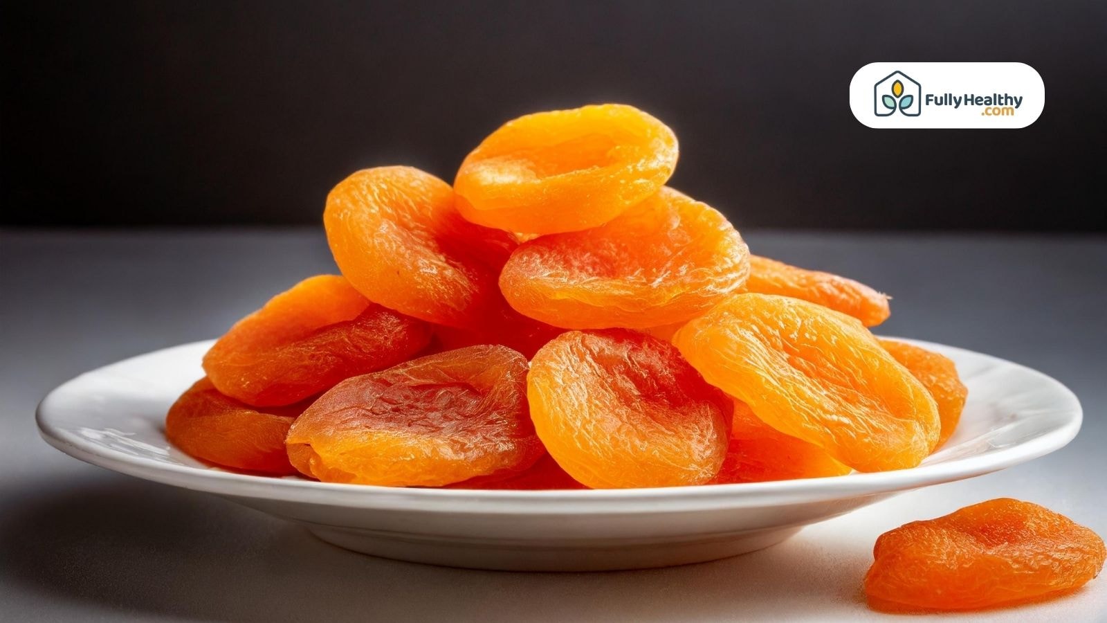 Dried apricots arranged on a white plate with dark background