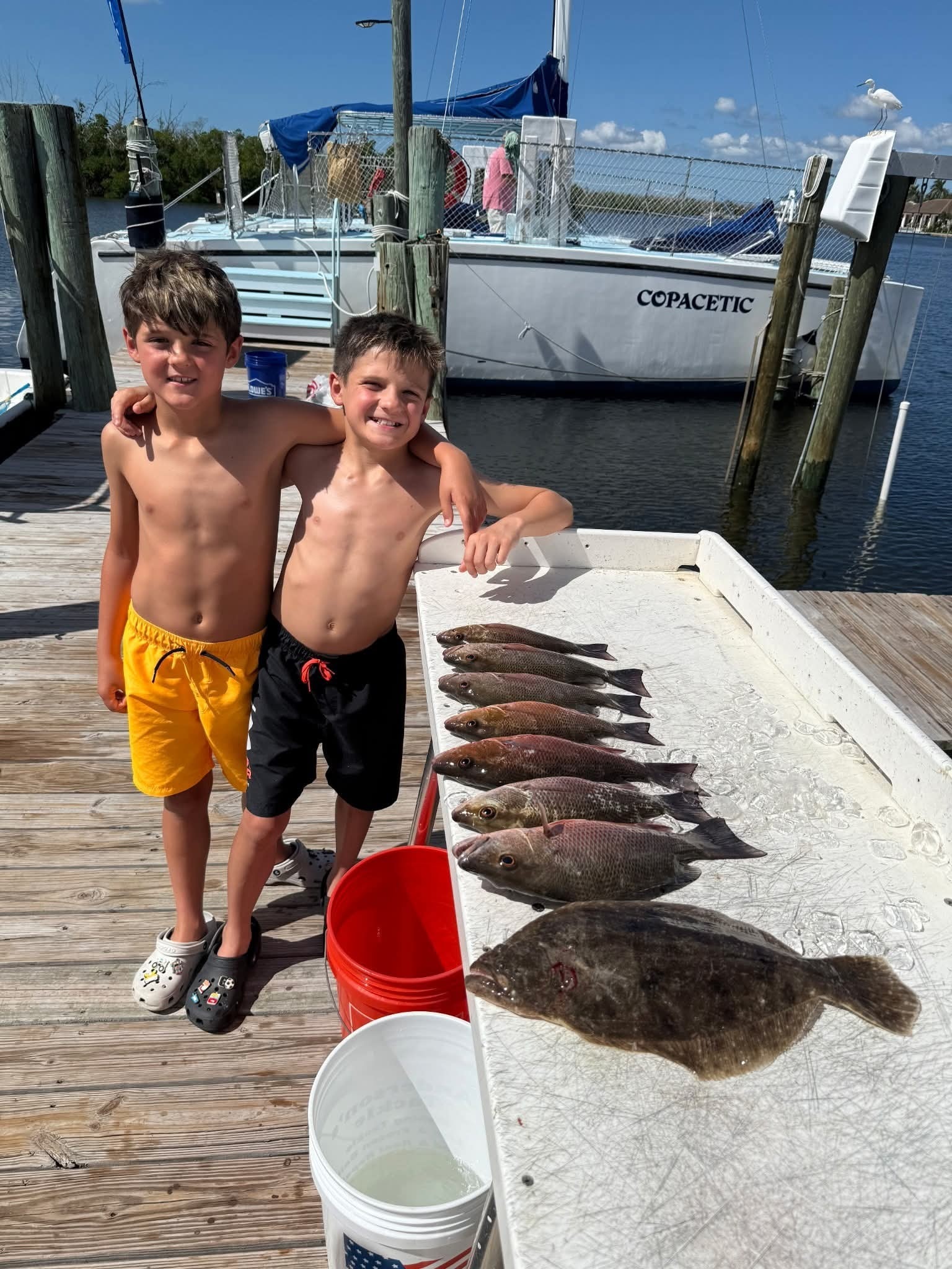 two boys at a table full of redfish, hoping to catch snook year round on the shore of gulf of mexico, florida