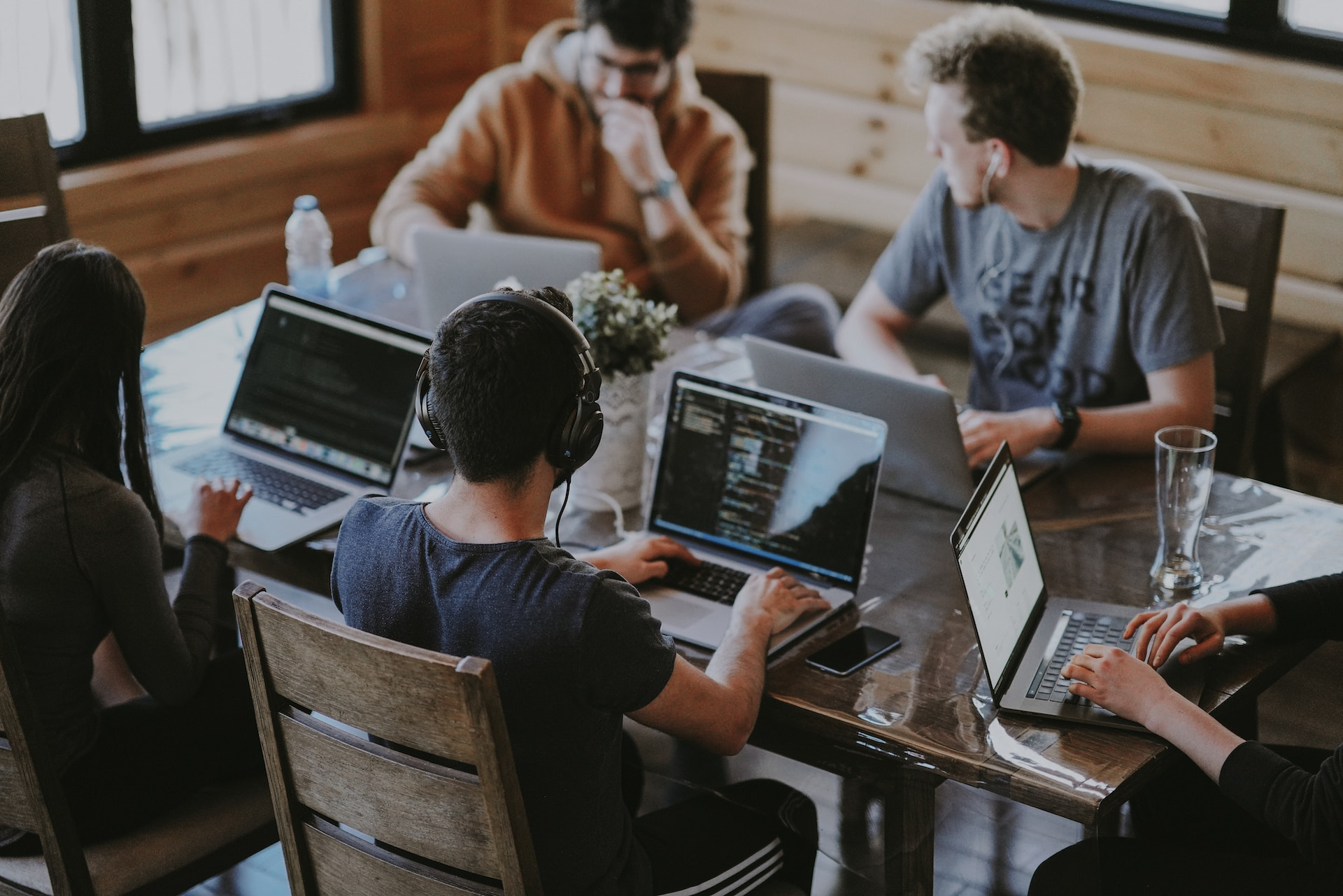 A team of website builders working at laptops in an office with a wooden table