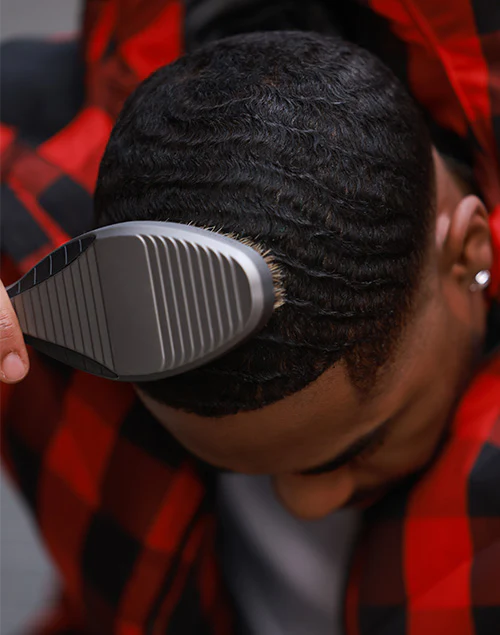 A person brushing their hair in a wave pattern with a wave brush