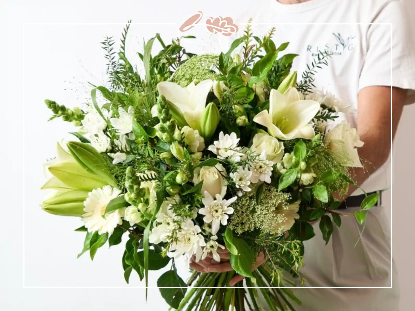 A vibrant bouquet of white lilies and greenery, elegantly arranged and held by a person. Fabulous Flowers and Gifts.