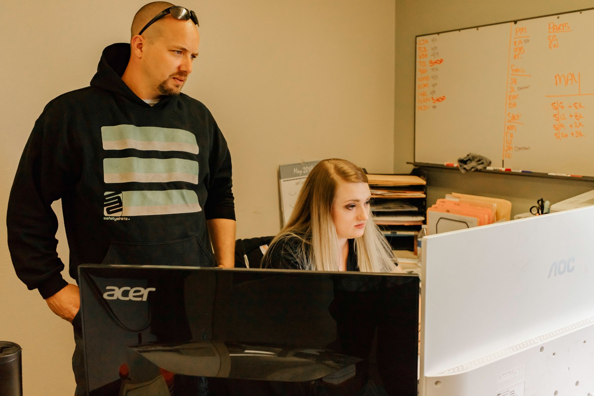 Employees with a whiteboard and computer in the background