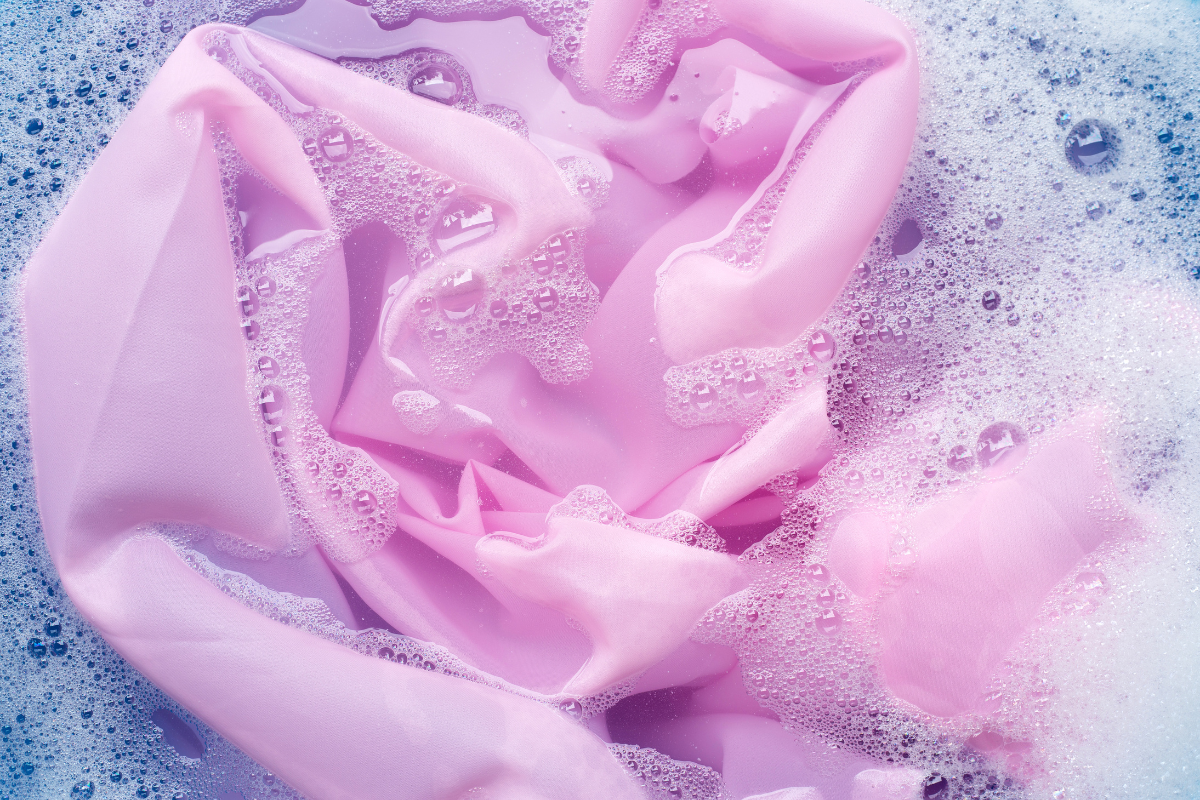 Foam cushions being hand-washed in a basin with soapy water