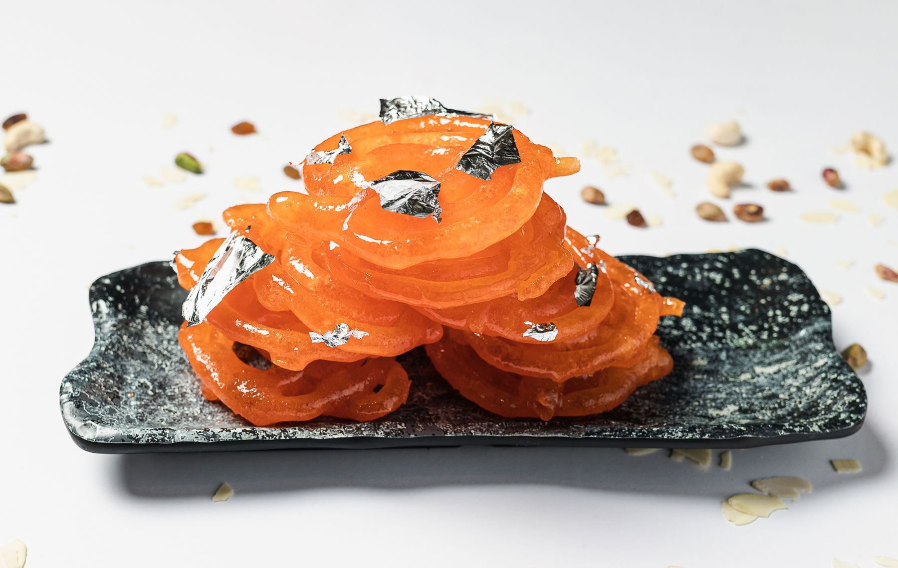 Golden swirls of Jalebi on a round plate, glistening with sugary syrup – a delectable Indian dessert.