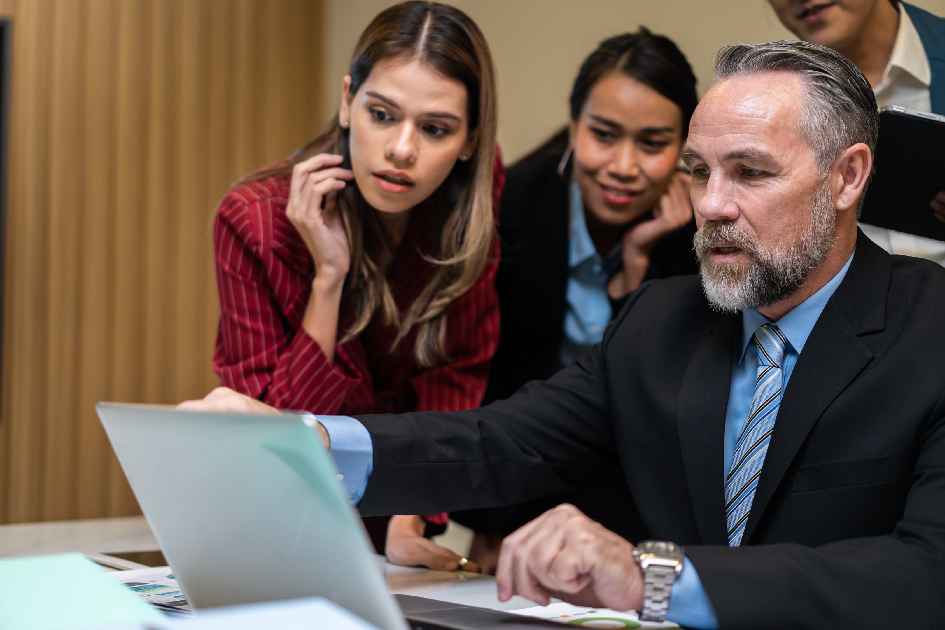 Employee cybersecurity training concept: employees gathering around a computer being trained on cybersecurity