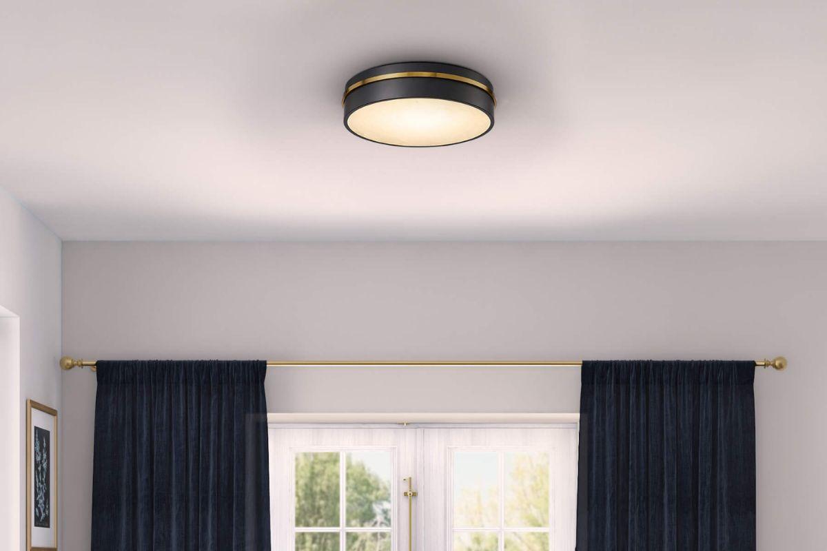 Black and brass flush mount ceiling light illuminating a home interior with navy curtains