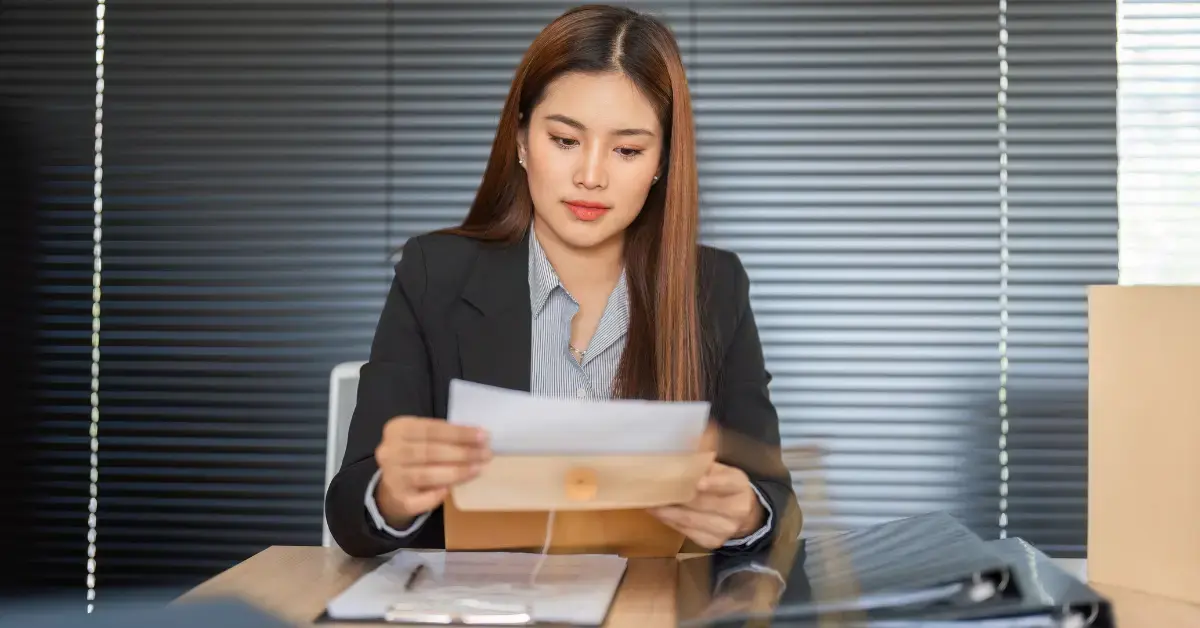 Female creator organizing Form 8822-B documents and EIN records before mailing IRS paperwork.