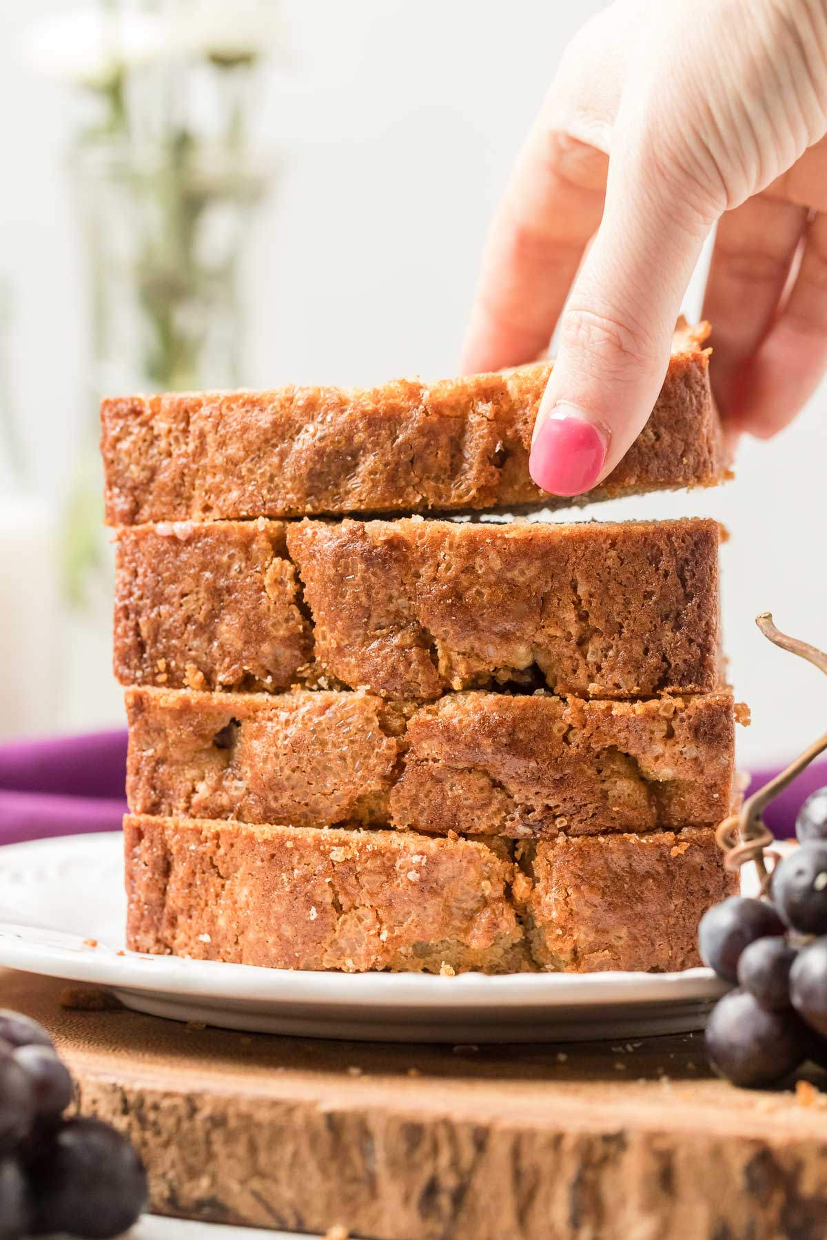 hand reaching for a slice of grape bread on a stack of slices